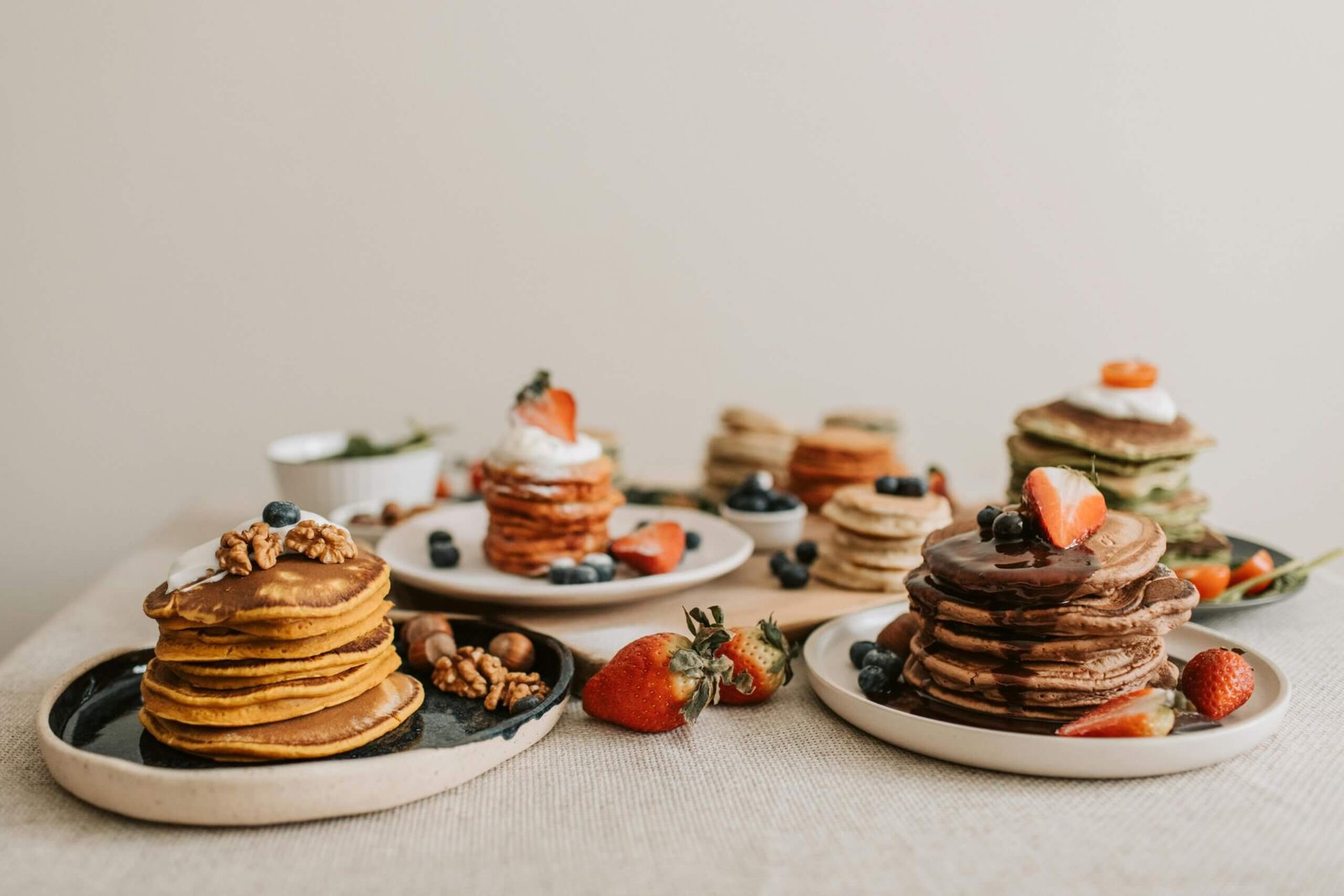 Delicious pancake assortment garnished with fresh berries and nuts, perfect for breakfast.