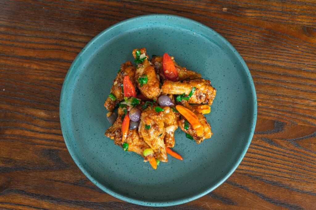 Top view of flavorful spicy chicken wings served on a blue plate with vegetables.
